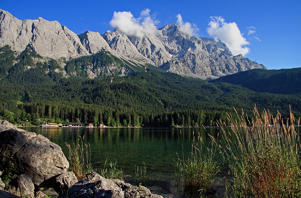The Eibsee lake with forested shore below the rocky north face of the Zugspitze.