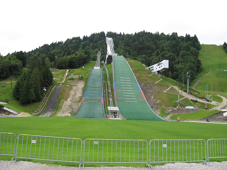 The landing slopes and towers of the Olympic ski jumps rising against a wooded hillside.